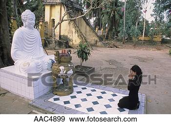 Stock Photograph - woman kneeling 
bfore a buddha 
statue and praying 
in vietnam. fotosearch 
- search stock 
photos, pictures, 
images, and photo 
clipart