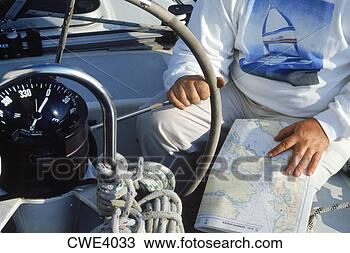 Stock Photo - man at helm of 
sailboat with 
wheel and compass 
and charts. fotosearch 
- search stock 
photos, pictures, 
images, and photo 
clipart
