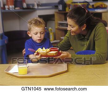 Stock Image of Daycare worker helping your male caucasian child...