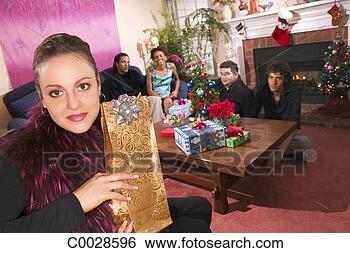 Stock Photo - a woman holds 
a gift and looks 
at the viewer 
while her friends 
sit in. fotosearch 
- search stock 
photos, pictures, 
images, and photo 
clipart