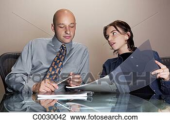 Stock Photo - a man and woman 
sit working together 
on a project, 
looking at a file. 
fotosearch - search 
stock photos, 
pictures, images, 
and photo clipart