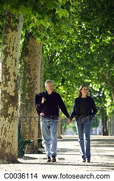 Stock Photo - a couple holding 
hands walking 
down a tree lined 
path in a park 
in. fotosearch 
- search stock 
photos, pictures, 
images, and photo 
clipart