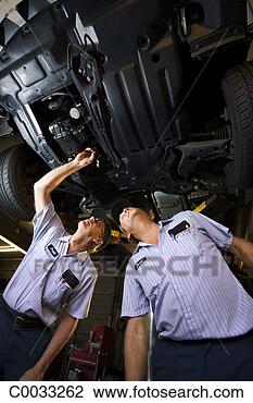 Stock Photo - low angle of two 
mechanics talking 
about the car 
on the car lift. 
fotosearch - search 
stock photos, 
pictures, images, 
and photo clipart