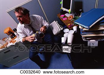 Stock Photography - a stressed out 
man sitting in 
messy work area 
holding a coffee 
cup. fotosearch 
- search stock 
photos, pictures, 
images, and photo 
clipart