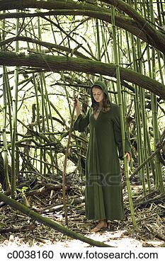 Stock Photography - green caped woman 
standing amidst 
branches and bamboo 
holding a stick. 
fotosearch - search 
stock photos, 
pictures, images, 
and photo clipart