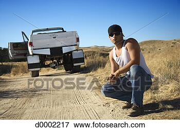 Picture - man crouching 
on dirt road. 
fotosearch - search 
stock photos, 
pictures, images, 
and photo clipart