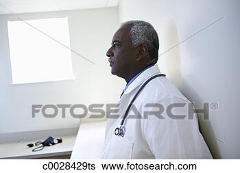 Stock Photo - backlit profile 
of a doctor leaning 
against the wall, 
 dealing with. 
fotosearch - search 
stock photos, 
pictures, images, 
and photo clipart