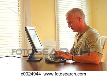 Stock Photo - side view of a 
man working on 
his computer at 
home. fotosearch 
- search stock 
photos, pictures, 
images, and photo 
clipart