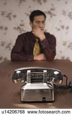 Banco de Imagem - jovem,  sentando, 
 atrás de,  telefone. 
fotosearch - busca 
de fotos, imagens 
e clipart