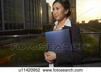 Stock Photo - young businesswoman 
standing in street, 
 holding file, 
 smiling. fotosearch 
- search stock 
photos, pictures, 
images, and photo 
clipart