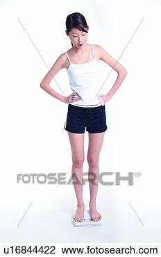 Stock Photo - young woman standing 
on weight scale, 
full length, hands 
on waist. fotosearch 
- search stock 
photos, pictures, 
images, and photo 
clipart
