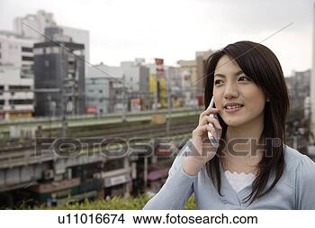 Stock Photo - view of a smiling 
young woman using 
mobile phone. 
fotosearch - search 
stock photos, 
pictures, images, 
and photo clipart