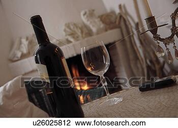 Stock Photo - bottle and glass 
of wine on a table 
in front of the 
fireplace. fotosearch 
- search stock 
photos, pictures, 
images, and photo 
clipart