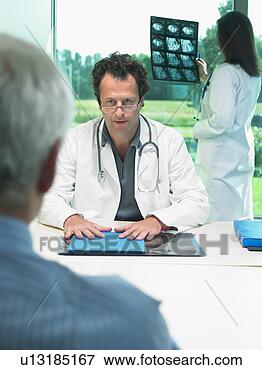 Picture - two doctors discussing 
x-rays with mature 
patient. fotosearch 
- search stock 
photos, pictures, 
images, and photo 
clipart