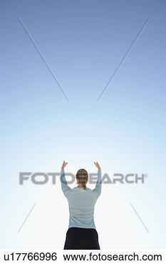 Stock Photo - young woman with 
raised arms against 
clear sky (rear 
view,  low angle. 
fotosearch - search 
stock photos, 
pictures, images, 
and photo clipart
