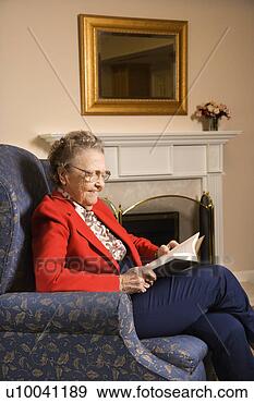 Stock Photograph - elderly caucasian 
woman reading 
book in chair 
at retirement 
community. fotosearch 
- search stock 
photos, pictures, 
images, and photo 
clipart