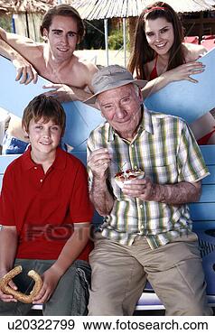 Arquivo Fotográficos - avô,  neto,  jovem, 
 par,  comer, 
 praia. fotosearch 
- busca de fotos, 
imagens e clipart