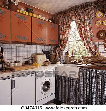 Stock Images of Checked curtains below sink in small kitchen with ...