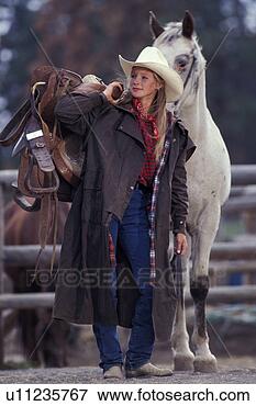 Picture - woman carrying 
saddle and standing 
with horse. fotosearch 
- search stock 
photos, pictures, 
images, and photo 
clipart