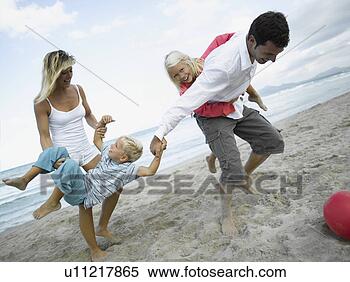 Stock Image - mid adult couple 
and their children 
playing on the 
beach. fotosearch 
- search stock 
photos, pictures, 
images, and photo 
clipart