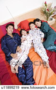 Stock Photograph - portrait of two 
parents lying 
on the bed with 
their two children. 
fotosearch - search 
stock photos, 
pictures, images, 
and photo clipart