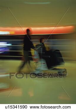 Stock Photography - travelers walking 
with luggage cart 
at airport, blurred 
motion. fotosearch 
- search stock 
photos, pictures, 
images, and photo 
clipart