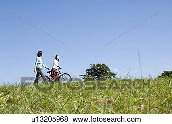 Banco de Imagem - dois,  jovem, 
 mulheres,  andar, 
 um,  empurrar, 
 bicicleta. fotosearch 
- busca de fotos, 
imagens e clipart
