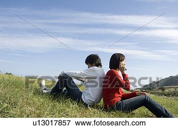 Foto - jovem,  par,  
sentando,  costas, 
 costas. fotosearch 
- busca de fotos, 
imagens e clipart