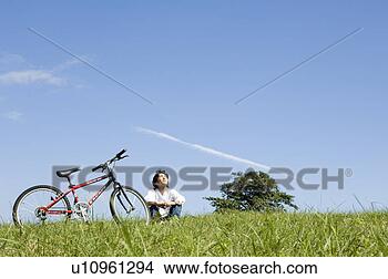Banco de Imagem - jovem,  sentando, 
 logo,  bicicleta. 
fotosearch - busca 
de fotos, imagens 
e clipart