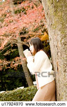 Stock Photography - young woman standing 
under tree. fotosearch 
- search stock 
photos, pictures, 
images, and photo 
clipart