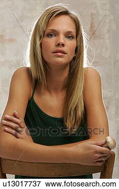 Foto - jovem,  mulher, 
 sentando,  cadeira, 
 braços,  backrest, 
 segurando. fotosearch 
- busca de fotos, 
imagens e clipart