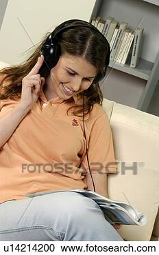Arquivo de Fotografias - jovem,  mulher, 
 sofá,  escutar, 
 música,  leitura, 
 revista. fotosearch 
- busca de fotos, 
imagens e clipart