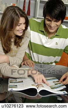 Stock Photo - young couple in 
their living room, 
looking at travel 
brochure. fotosearch 
- search stock 
photos, pictures, 
images, and photo 
clipart