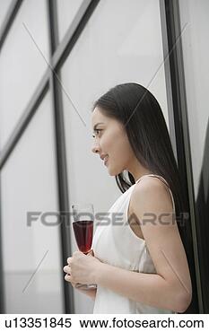Stock Image - young woman holding 
a glass of champagne 
in front of mirror. 
fotosearch - search 
stock photos, 
pictures, images, 
and photo clipart