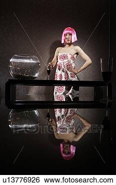 Stock Photo - young woman wearing 
a pink hairpiece, 
 posing beside 
a fishbowl in. 
fotosearch - search 
stock photos, 
pictures, images, 
and photo clipart