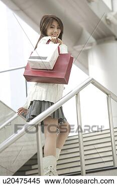 Stock Image - young woman walking 
upstairs with 
paper bags, turning 
head smiling. 
fotosearch - search 
stock photos, 
pictures, images, 
and photo clipart