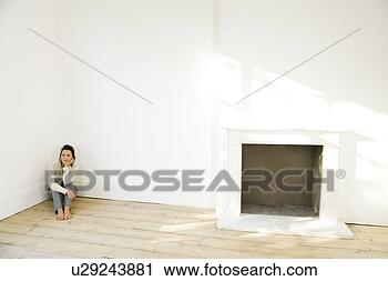 Stock Photography - a young woman sitting in the corner of an empty room. fotosearch - search stock photos, pictures, images, and photo clipart