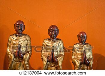 Stock Photo - three wooden statues 
of buddhist disciples 
against orange 
wall. fotosearch 
- search stock 
photos, pictures, 
images, and photo 
clipart