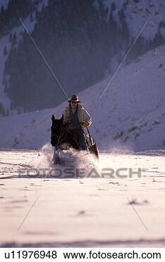 Stock Photo - cowboy riding 
a horse through 
snow. fotosearch 
- search stock 
photos, pictures, 
images, and photo 
clipart