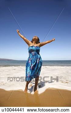 Stock Photography - young-adult black 
woman standing 
in shore with 
arms stretched. 
fotosearch - search 
stock photos, 
pictures, images, 
and photo clipart