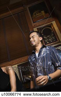 Stock Photo - young hispanic 
man laughing and 
drinking beer 
at pub. fotosearch 
- search stock 
photos, pictures, 
images, and photo 
clipart