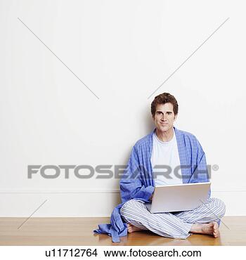 Stock Photo - portrait of a 
mature man sitting 
cross-legged on 
the floor and 
using. fotosearch 
- search stock 
photos, pictures, 
images, and photo 
clipart