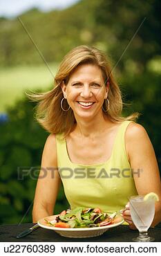 Stock Photograph - portrait of a 
mature woman sitting 
at the table with 
a plate of. fotosearch 
- search stock 
photos, pictures, 
images, and photo 
clipart