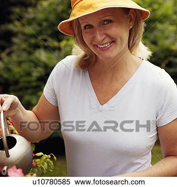 Stock Image - portrait of a 
mature woman watering 
plants and smiling. 
fotosearch - search 
stock photos, 
pictures, images, 
and photo clipart