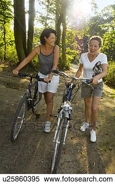 Stock Image - two women walking 
with cycles. fotosearch 
- search stock 
photos, pictures, 
images, and photo 
clipart