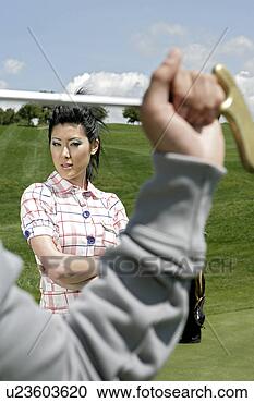 Stock Photography - view of  a young 
woman, person 
holding a golf 
club. fotosearch 
- search stock 
photos, pictures, 
images, and photo 
clipart