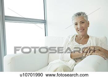 Stock Photography - mature woman sitting 
with her legs 
crossed in a white 
chair. fotosearch 
- search stock 
photos, pictures, 
images, and photo 
clipart