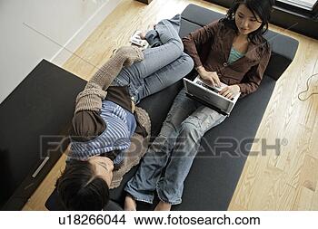 Stock Photo - one young woman 
using laptop, 
young man lying 
beside, high angle 
view. fotosearch 
- search stock 
photos, pictures, 
images, and photo 
clipart