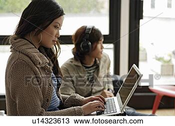 Stock Photo - woman working 
on laptop, man 
listening to music. 
fotosearch - search 
stock photos, 
pictures, images, 
and photo clipart