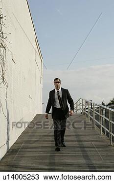 Stock Photo - man in a suit 
walking down a 
boardwalk. fotosearch 
- search stock 
photos, pictures, 
images, and photo 
clipart